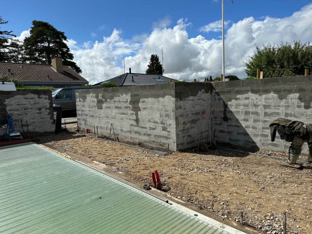 En mur, der ikke er færdig endnu, lavet af grå betonblokke, som en murer i Næstved har lagt