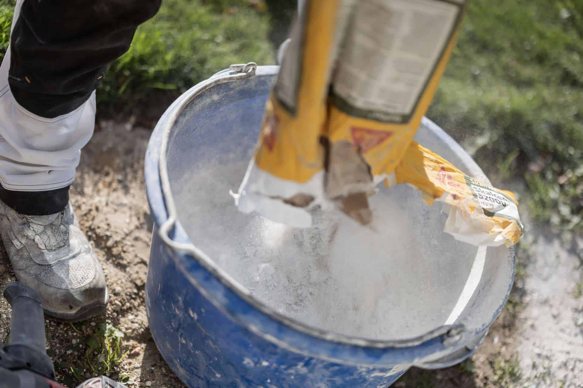 Hvidt mørtelpulver blandes i en spand til reparation af fuger i murværk for NH Murerentreprise